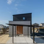 スタイリッシュな黒とグレーのモダンな外観デザインと、カーポートを備えたモダンな注文住宅